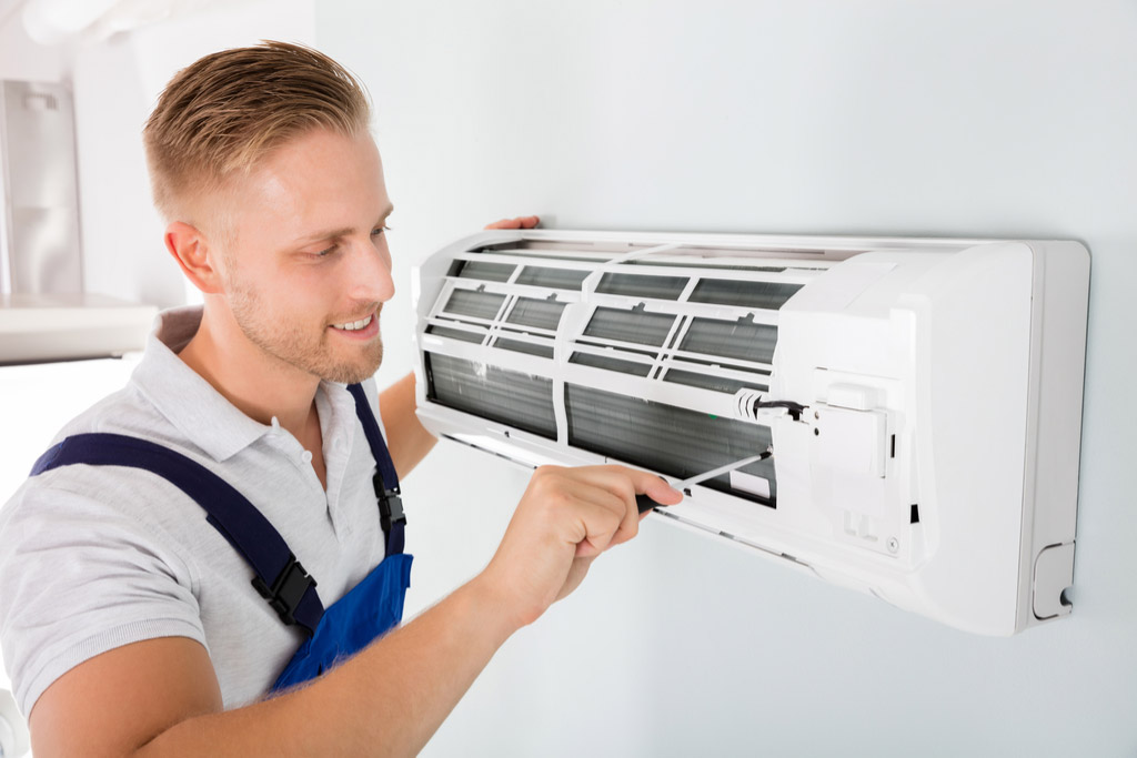 HVAC technician cleaning and repairing a ductless mini split AC in Evans, CO