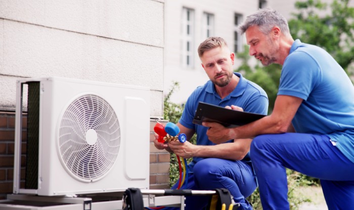 HVAC technicians reviewing an outdoor air conditioning unit in Evans, CO