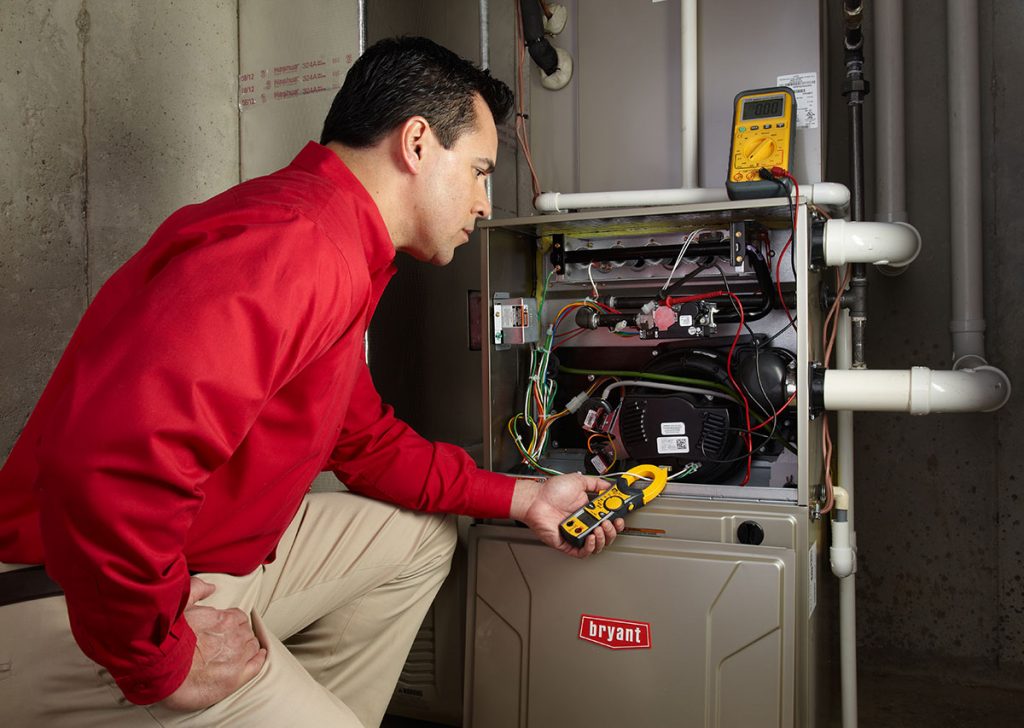 Heating and air conditioning technician servicing an indoor furnace in Evans, CO