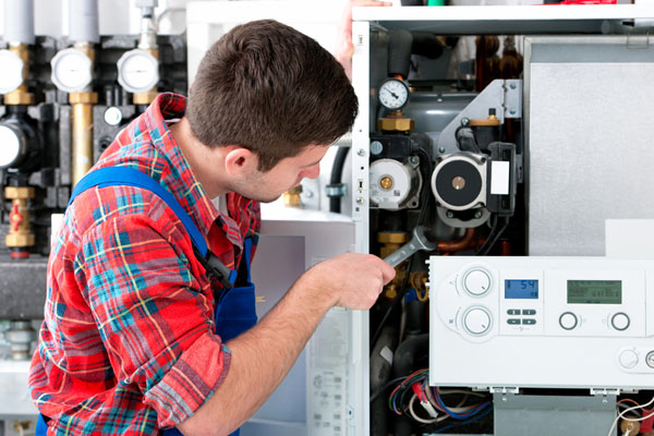 HVAC technician inspecting and repairing boiler controls in Evans