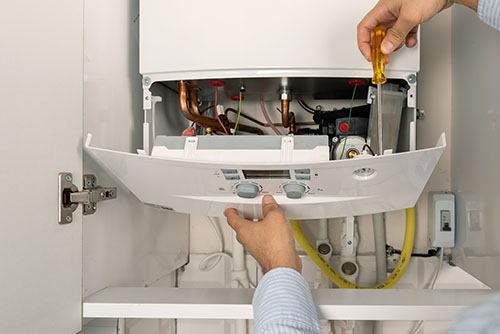 HVAC technician repairing an indoor boiler in Evans