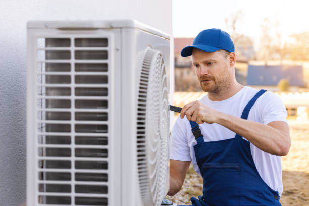 HVAC technician servicing an outdoor air conditioning unit in Evans
