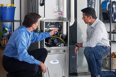 HVAC technician explaining furnace repair and maintenance to a homeowner in Evans, CO