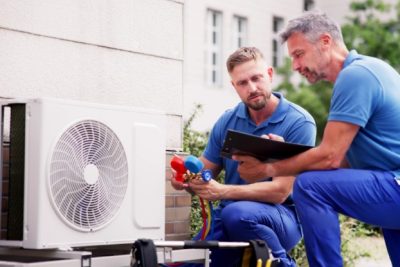 HVAC technicians reviewing an outdoor air conditioning unit in Evans, CO