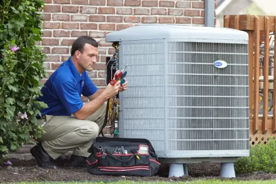 HVAC technician inspecting an outdoor air conditioning unit in Evans, CO