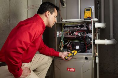 Heating and air conditioning technician servicing an indoor furnace in Evans, CO